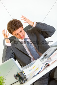 Confused modern businessman lost in documents
