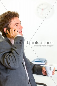 Serious businessman in office talking mobile
