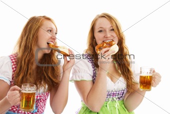 two bavarian women eating pretzels and holding beer