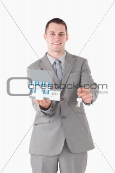 Portrait of a smiling businessman showing a miniature house and keys