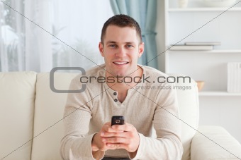 Man sending text messages while sitting on a sofa