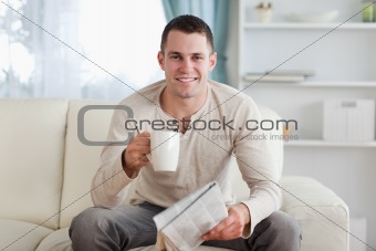 Man holding a newspaper while drinking a tea