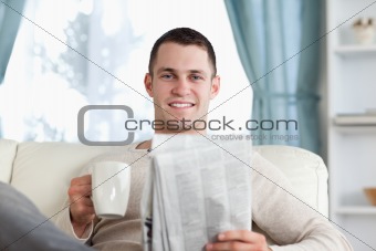 Young man having a tea while reading the news