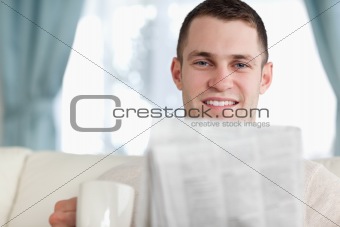 Handsome man having a coffee while reading the news