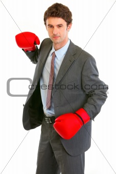 Serious modern businessman in boxing gloves brandishing to attack
