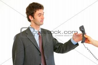 Serious modern businessman taking phone from secretaries hand
