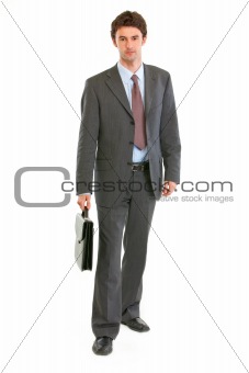 Confident modern businessman with suitcase making step
