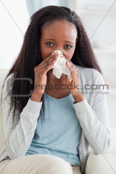 Close up of woman on couch blowing her nose
