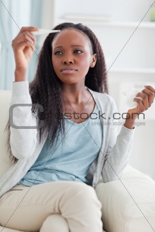 Woman measuring her temperature on sofa