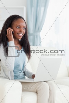 Woman on her phone while using laptop