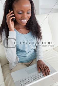 Close up of woman on the phone while using notebook
