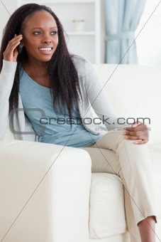 Woman sitting on sofa while using her mobile phone