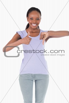Close up of woman giving one thumb up and one down on white background