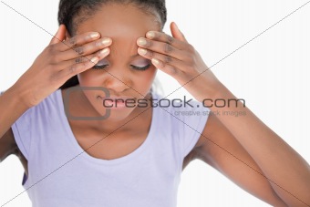Close up of woman rubbing her temples against a white background