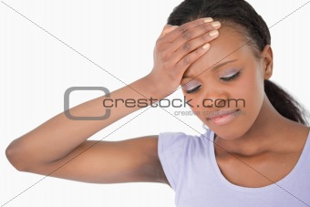 Close up of woman holding her forehead against white background