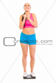 Satisfied with her weight young girl standing on floor scale
