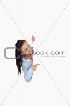 Businesswoman pointing while looking around the corner