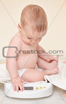 Cute baby check own weight on home scales