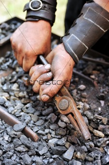 Detail of dirty hands holding pliers - blacksmith