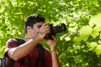 young male photographer hiking in forest 