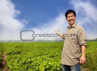 happy asian farmer showing his farm