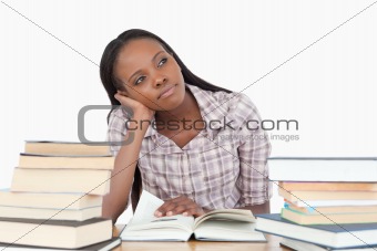 Young woman daydreaming next to stack of book