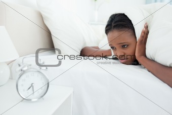 Tired woman being awakened by her alarm clock