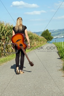 Guitarist walking down country road