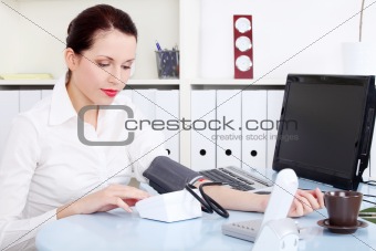 Businesswoman measuring her blood pressure.