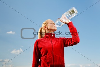 Young woman drinking water from plastic bottle