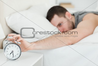 Brown-haired man being awakened by an alarm clock