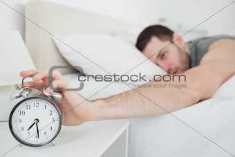 Young man being awakened by an alarm clock