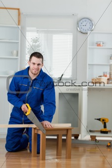 Portrait of a smiling handyman cutting a wooden board