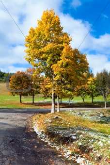 First winter snow and autumn colorful foliage near mountain road