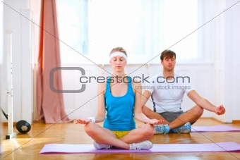 Young man and fit woman doing yoga at home
