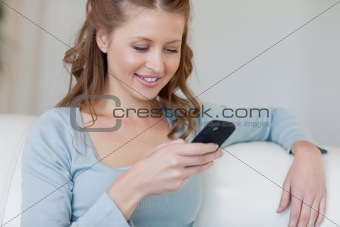 Woman on the sofa reading text message on her smartphone