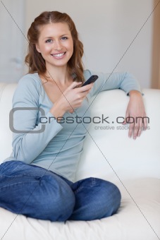 Smiling woman on the couch typing text message