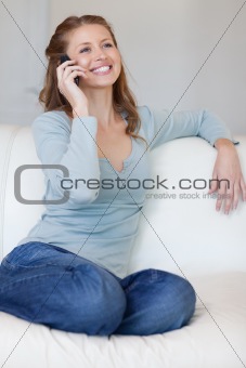 Smiling woman on the sofa answering the phone