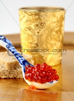 Fresh red caviar  in  spoon  on gold background