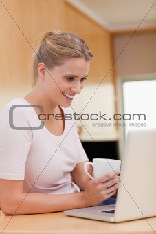 Portrait of a woman using a notebook while drinking a cup of a tea