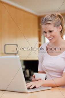 Portrait of a woman using a laptop while drinking tea
