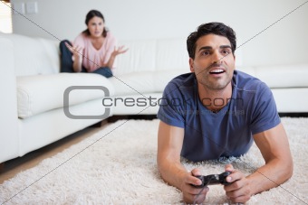 Man playing video games while his fiance is getting mad at him