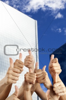 people's hand with thumbs up in front of modern building