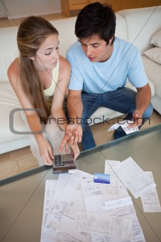 Portrait of a sad couple looking at their receipts