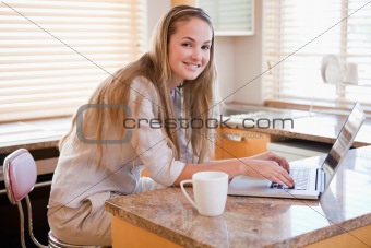 Woman having coffee while using a laptop