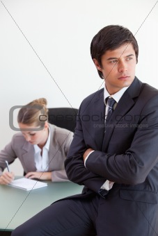 Portrait of a manager posing while his colleague is working