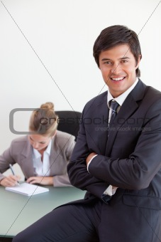 Portrait of an office worker posing while his colleague is working
