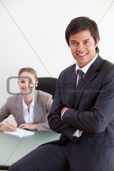 Portrait of a businessman posing while his colleague is working