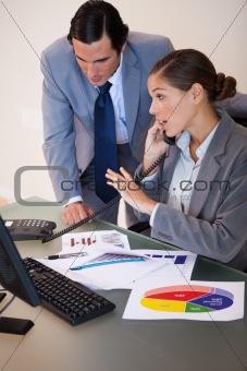 Businesswoman getting a phone call while analyzing statistics