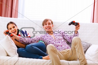 Young man taking joystick from his winning girlfriend while playing console
